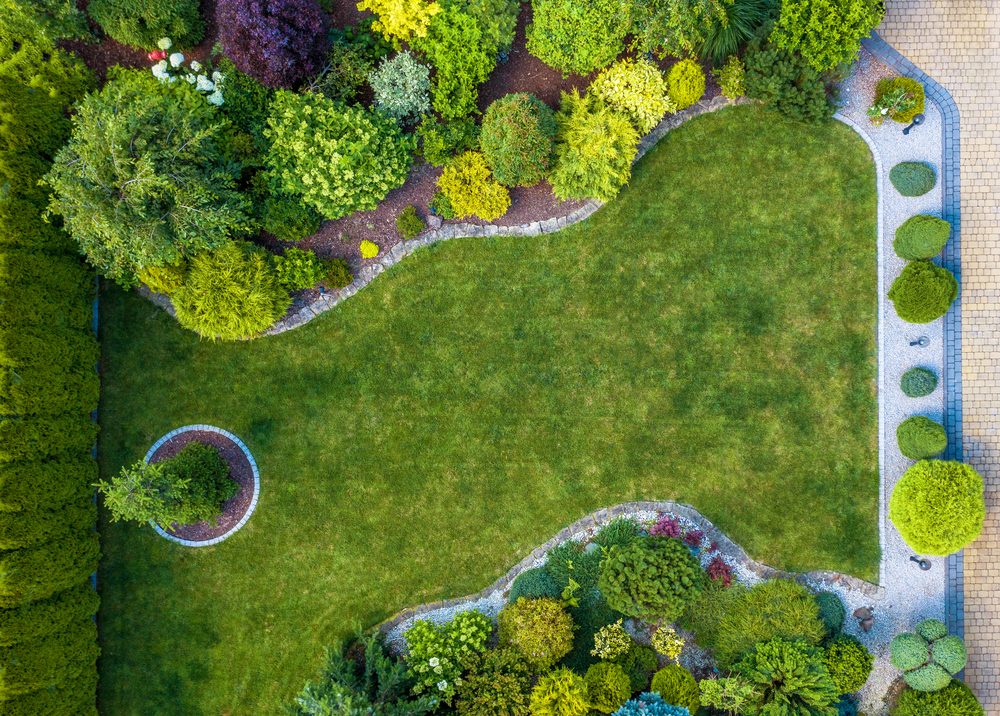 Aerial view of a lawn framed by curved planting beds and stone edging