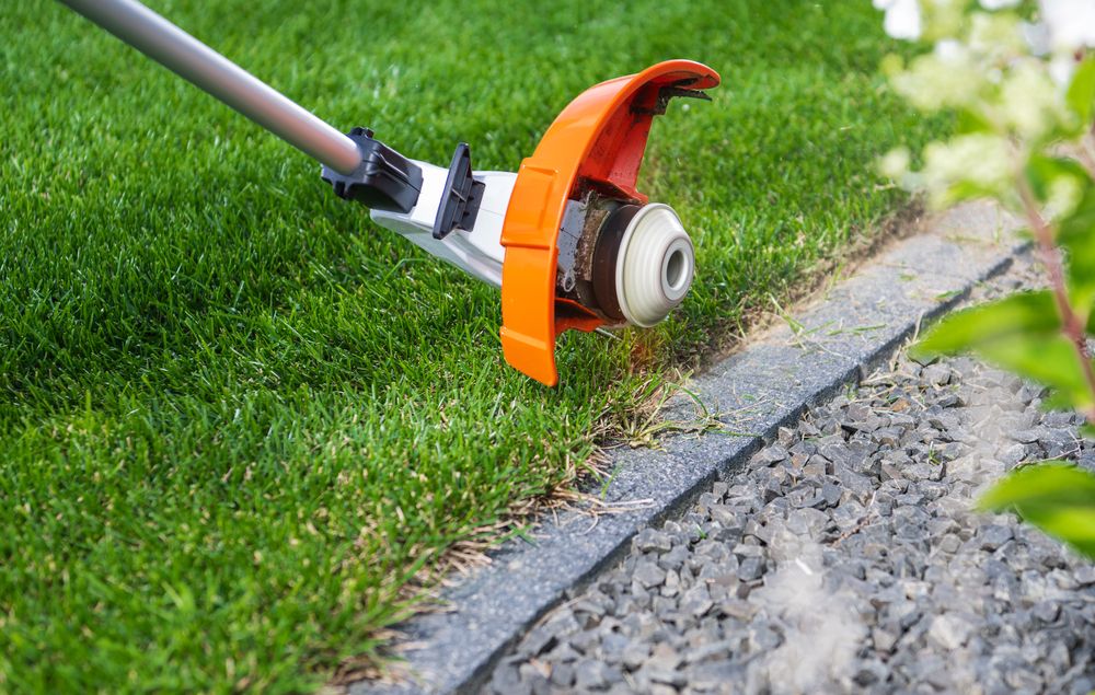 String trimmer edging grass along a stone border