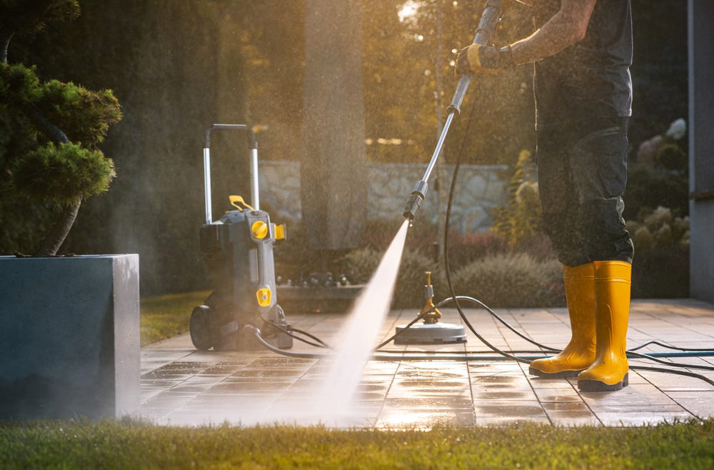 Pressure washer spraying a paver patio clean